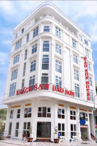 下龙湾Bảo Sơn Hotel的一座白色的大建筑,上面有红色的标志