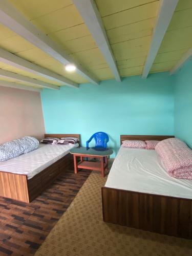 PanaotiMount Mahabharat Homestay的蓝色墙壁客房的两张床
