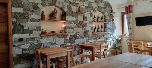 布吕松Le Coin des Mélèzes - NATURE & TREK的一间设有木桌和石墙的餐厅