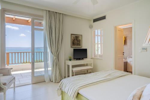 阿尔米里达SK Place Luxury Seafront Villas Chania的一间卧室配有一张床、一台电视和一个阳台