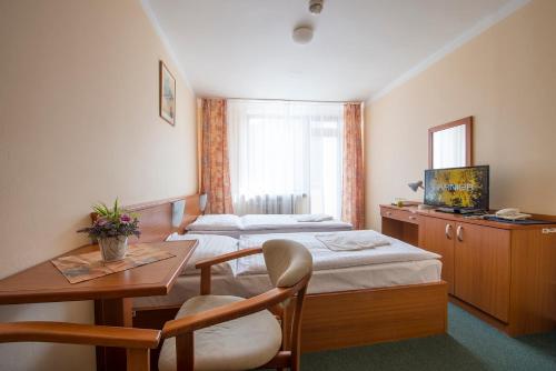 迪马诺卡多林纳Hotel SOREA SNP的酒店客房设有两张床、一张桌子和一张书桌。