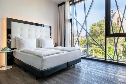 莱比锡INNSiDE by Meliá Leipzig的卧室配有白色的床和大窗户