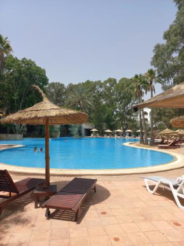 哈马马特Tunisia Lodge的游泳池配有椅子、遮阳伞和桌子