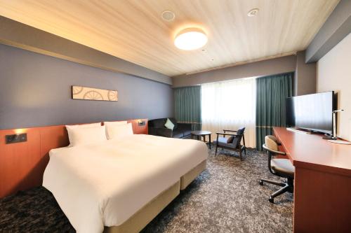 横滨横滨马车道里士满酒店的酒店客房设有一张大床和一张书桌。