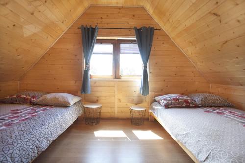 尼彻兹LAZUROWY ZAKĄTEK的小木屋内的两张床,设有窗户