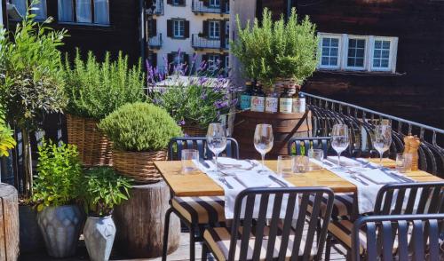 采尔马特博斯托特色酒店的植物阳台的桌子和酒杯