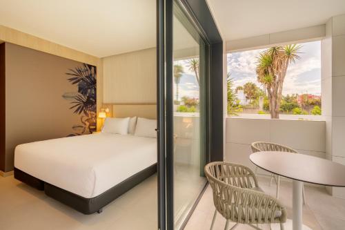 马贝拉Eurostars Oasis Marbella的卧室配有一张床和一张桌子及椅子