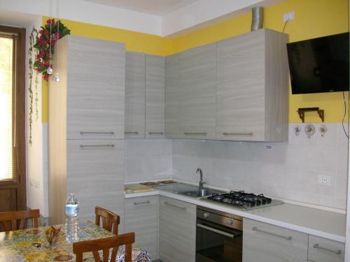特拉西梅诺湖畔托罗La Poventa的厨房配有白色橱柜、水槽和桌子