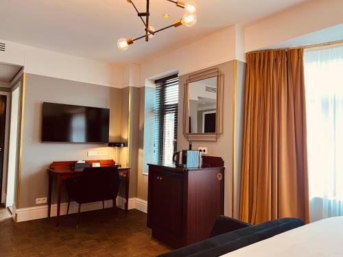 布兰肯贝赫Gatsby Hotel - Adults Only - Small Luxury Hotel - by F-Hotels的酒店客房配有一张床、一张书桌和一台电视。
