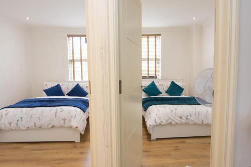 伦敦Evergreen Apartments-Flat 4, London的一间卧室配有两张带蓝色枕头的床