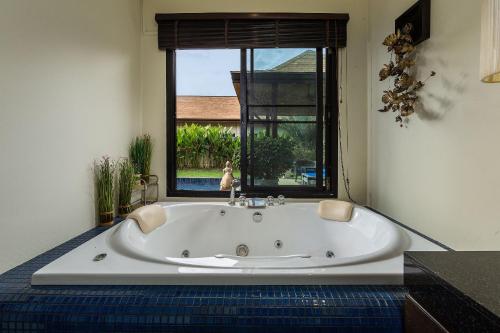 奈汉海滩马拉马别墅 - 由TropicLook经营：科阳风格奈汉海滩的窗户客房内的白色浴缸