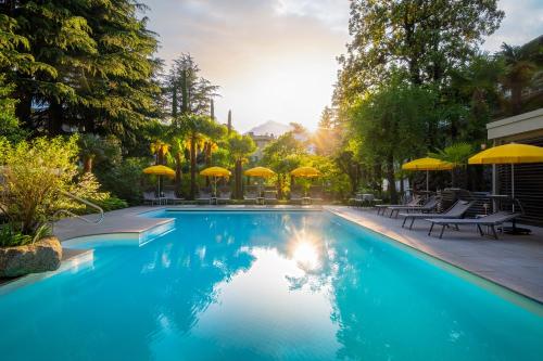 梅拉诺Villa Bavaria的一个带遮阳伞和桌椅的游泳池