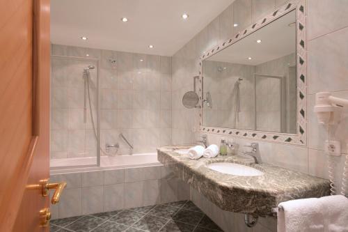 圣安东阿尔贝格珀斯特酒店的一间带水槽、浴缸和镜子的浴室