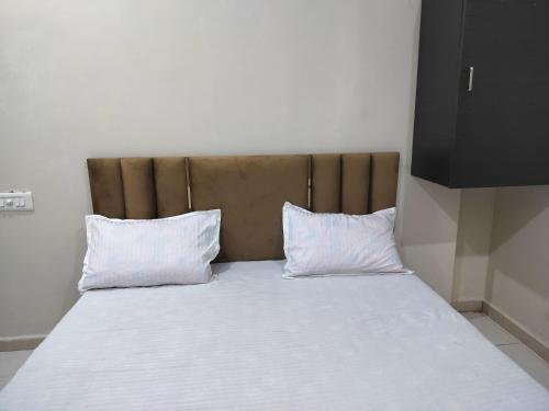 乌贾因Satkar home stay的一张大床,上面有两个白色枕头