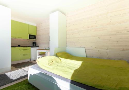 图尔库Yksiö Turun Hirvensalossa的一间带绿色床的卧室和一间厨房