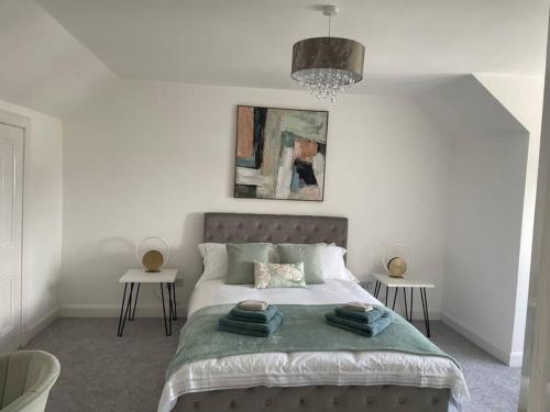 波尔蒙特Fantastic home in Brightons, Falkirk.的一间卧室配有一张大床和两张桌子
