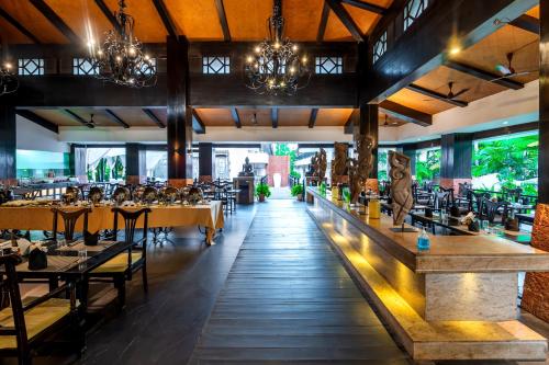 坎多林O Hotel Goa, Candolim Beach的一间带桌椅的餐厅和一间酒吧