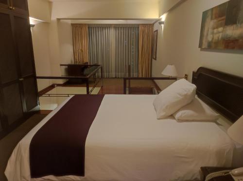 利马Miraflores Confort Suite的卧室配有一张白色大床和一张书桌