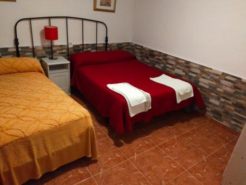 CarrenoPensión Tabaza的一间卧室配有两张床和红色的床罩