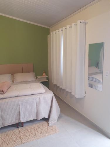 迪亚曼蒂纳Suíte privativa confortável的一间卧室配有床和带窗帘的窗户