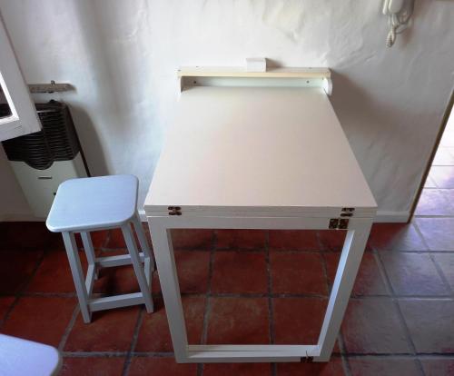 戈多伊克鲁斯Departamento 1º P, 2 personas, WIFI, confortable, mucha luz natural的一张白色的桌子,墙上有凳子