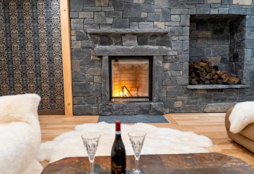 坎莫尔Luxury suite with Sauna and Spa Bath - Elkside Hideout B&B的客厅设有壁炉,提供一瓶葡萄酒