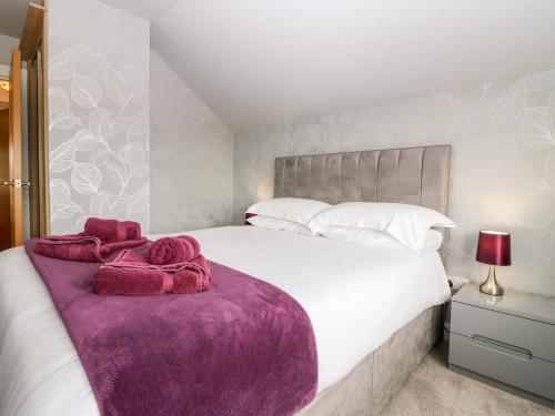 圣安德鲁斯Glebe Cottage Number 6的卧室配有一张白色大床和紫色毯子