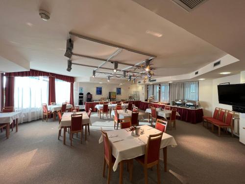埃格尔艾斯特拉高级酒店的餐厅设有桌椅和平面电视。