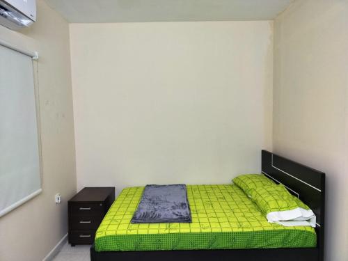 沙迦Prem Home Stay的一间卧室配有绿色的床和黑色橱柜