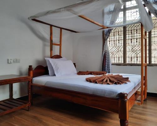 南威Kajificheni House的一间卧室配有一张木床和天篷