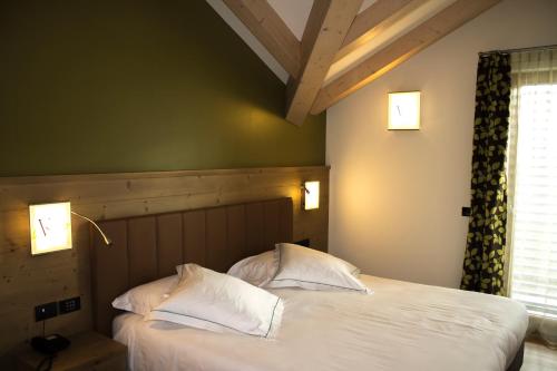 RevòViridis Hotel的一间卧室设有两张带白色床单的床和窗户。