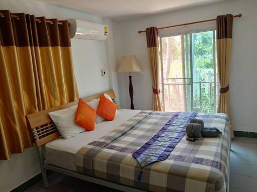 班克鲁特2-bed house near beach w/ aircon的一间卧室配有带橙色枕头的床和窗户。