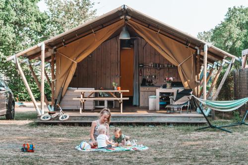 霍尔滕Glamping Holten luxe safaritent 1的一名妇女和两名儿童坐在帐篷前