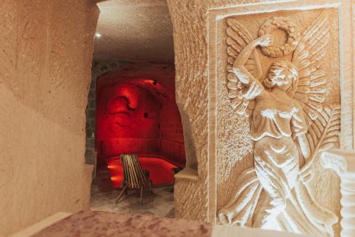 乌奇希萨尔Harem Suites Cappadocia的一间设有红色沙发的房间和天使雕像