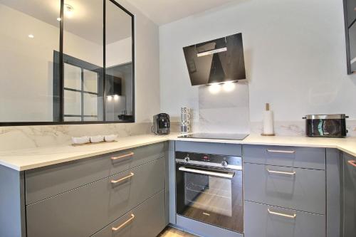 瓦讷L'Universel的厨房配有灰色橱柜、水槽和炉灶。