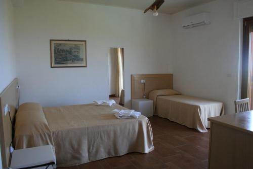 贝尔韦代雷Il Podere dell'Angelo Old Country House的酒店客房设有两张床和一张桌子。