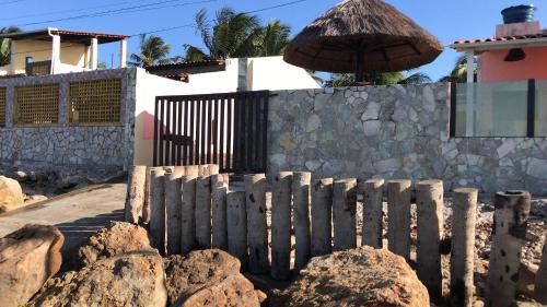 佩巴州蓬塔尔B&B Beach House Pousada Exclusiva pés na água Pontal do Peba única em Alagoas的房屋前有围栏,有岩石和雨伞