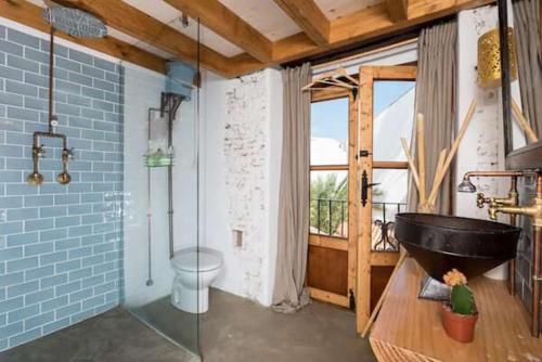 马贝拉The Farm Lodge的一间带玻璃淋浴和黑色浴缸的浴室