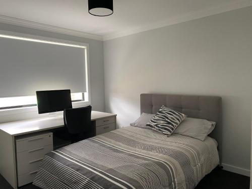KelsoEntire 4 bedroom home on Connolly in Bathurst的一间卧室配有一张床、一张书桌和一个窗户。