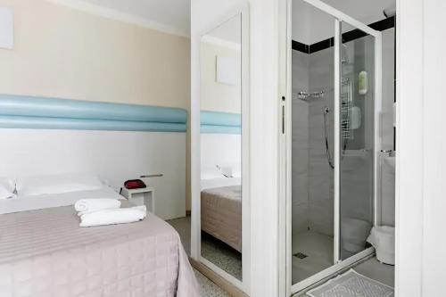 里米尼Hotel Villa Argia Rimini Marina Centro的浴室设有床铺和玻璃淋浴间。