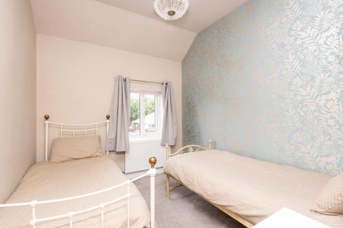 StanleyCanal Side Cottage Wakefield的一间卧室设有两张床和蓝色的墙壁