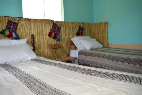 HuillanopampaTaquile Sumaq Wasi - Casa de Felipe e Ines的一间卧室设有两张床,墙上设有一扇