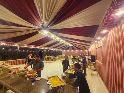 瓦迪拉姆Wadi Rum Aviva camp的餐厅的自助餐,包括人们准备食物