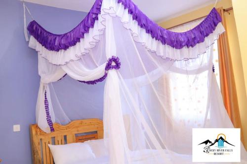 ThikaRocky river falls resort的一间卧室配有带紫色和白色窗帘的天篷