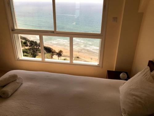 内坦亚尼茨萨海景公寓的一间卧室设有一张床和一个带海滩的窗户