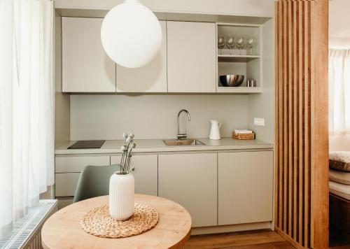 莫斯特拉纳Apartments Triglav的厨房配有白色橱柜和一张带花瓶的桌子