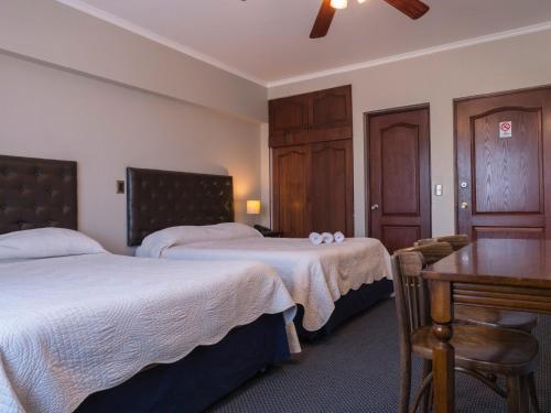 洛斯安赫莱斯Hotel Econohotel的酒店客房设有两张床和一张桌子。