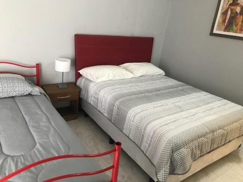 梅赛德斯comoencasa2的一间卧室设有两张床和红色床头板