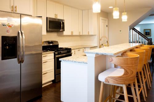 巴尔的摩Luxury Federal Hill Home with Rooftop & 4 Parking Spots的厨房配有不锈钢冰箱和酒吧凳