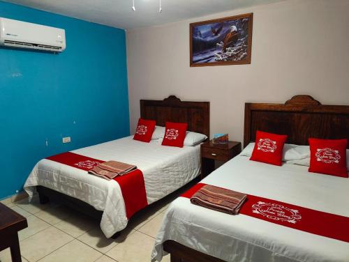 帕拉斯德拉富恩特Hotel Posada Santa Elena的酒店客房 - 带两张带红色枕头的床
